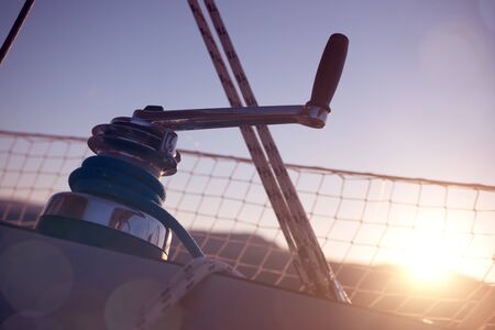Winch with rope on a sail boat close up and sunrise: vacations and sailing conceptの写真素材