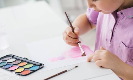 Cute happy girl painting with watercolors on a sheet, education and creativity conceptの写真素材