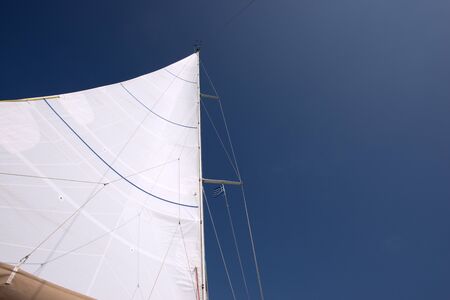 White sail against a clear blue sky: navigation and travel concept