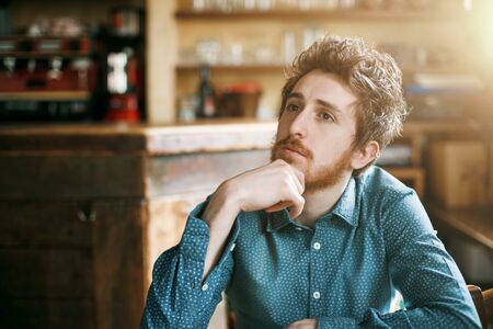 Young pensive hipster posing with hand on chin looking awayの写真素材