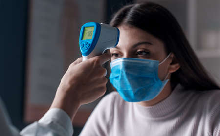 Body temperature check: doctor measuring temperature using an infrared thermometer gun