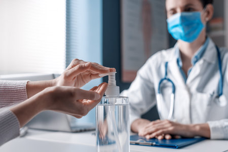 Patient sanitizing hands in the doctor's office using an antibacterial gel,  preventionの写真素材