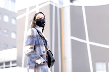 Young fashionable woman wearing a black face mask and posing outdoorsの写真素材