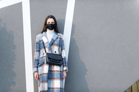 Young fashionable woman wearing a black face mask and posing outdoorsの写真素材