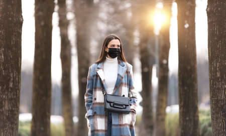 Young woman wearing a protective face mask and walking down the streetの写真素材