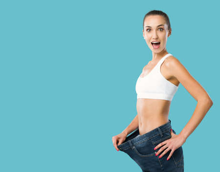 Happy woman showing her successful weight loss, her jeans are loose and she is slim, weight loss and fitness conceptの写真素材