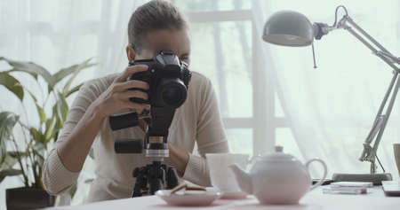 Professional photographer working from home, she is taking pictures of table setting with teapotの写真素材