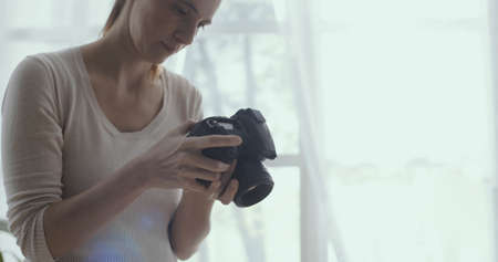 Professional female photographer working from home, she is checking camera settingsの写真素材