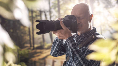 Professional wildlife photographer shooting in a forest with a digital camera