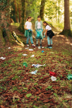Young cleanup volunteers picking up trash in the forest, environmental care conceptの写真素材