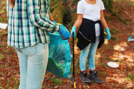 Young cleanup volunteers picking up trash in the forest, environmental care conceptの写真素材