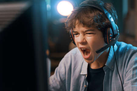Young gamer connecting online and playing online video games, he is excited and shouting