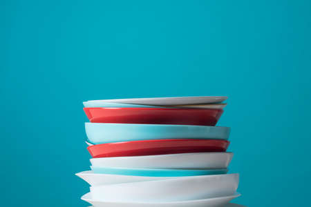 Pile of colorful clean dishes on light blue backgroundの写真素材