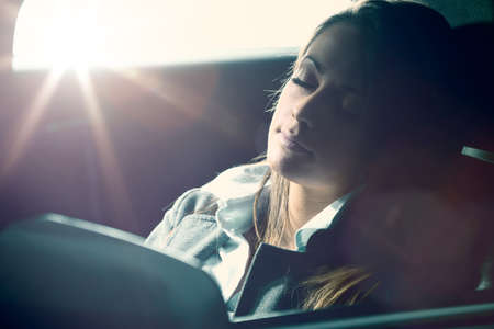 Exhausted young woman sleeping in a car with eyes closed.の写真素材