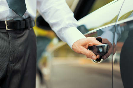 Businessman opening a car door, hand on handle close up, business and dealership concept