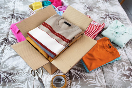 Piles of t-shirts and open delivery box on the bed