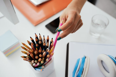 Young designer sitting at desk and working, she is taking a colored pencil, creativity and imagination conceptの写真素材