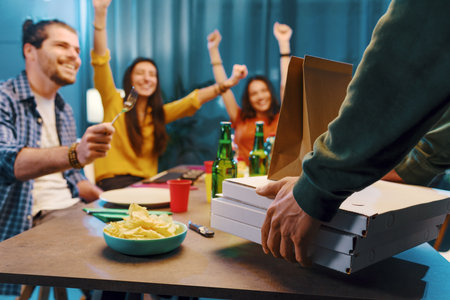Group of friends eating pizza together at home, fast food and food delivery conceptの写真素材
