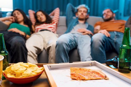Lazy friends napping on the couch after eating pizza together