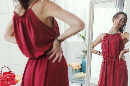 Confident woman trying a new outfit and getting ready to go out, she is looking at herself in a mirrorの写真素材