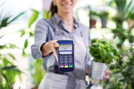 Smiling florist showing a POS terminal, electronic payments and commerce concept