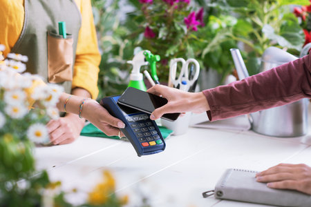 Customer paying in a flower shop using her smartphone, electronic payments conceptの写真素材