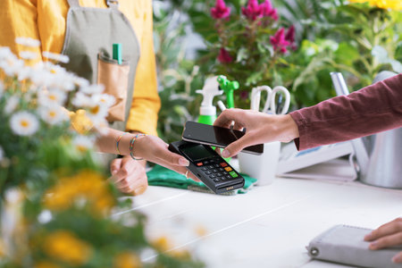 Customer paying in a flower shop using her smartphone, electronic payments conceptの写真素材