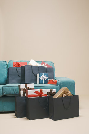 Many gifts and shopping bags at home next to a couch, sale and festivity conceptの写真素材