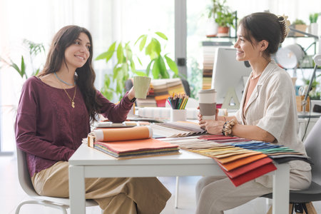 Smiling young designers in their office, they are having a coffee break togetherの写真素材