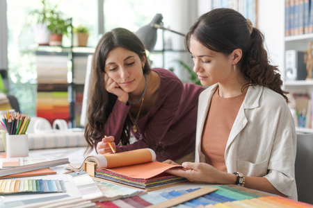 Young professional interior designers and decorators working on a project: they are checking swatches and choosing the perfect color palette, creativity conceptの写真素材