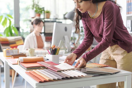 Professional designer working in the office, she is choosing fabric swatches for her creative projectの写真素材