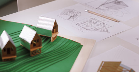 An architect's desk, on which a model of his project and design sketches can be seen