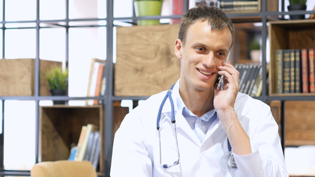 Handsome mature medical doctor consulting with patient on smartphoneの写真素材