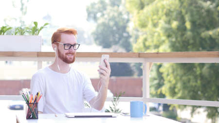 Online Video Chat on Smartphone, Sitting Outdoorの写真素材