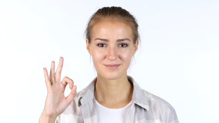OK sign by a young girl in front of white backgroundの写真素材