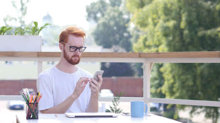 Man Using Smartphone, Sitting  Outdoorの写真素材
