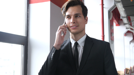 Walking Man in Suit Talking on Phone with Customerの写真素材