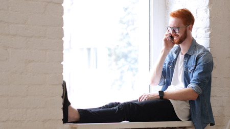 Answering Phone Call, Talk by Designer, Sitting in Window, Red Hairs and Beardの写真素材