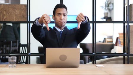 Thumbs Down by Black Businessman while Working on Laptopの写真素材