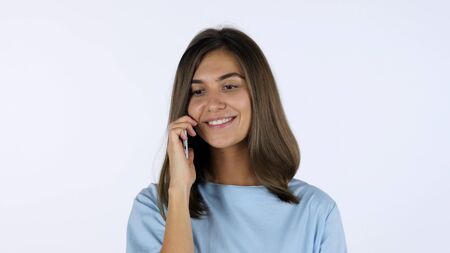 Smiling Girl Talking on Phone, White Background in Studioの写真素材