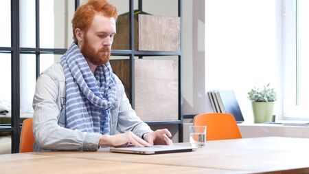 Beard Man Opening Laptop to Start Workの写真素材