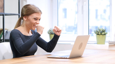 Excitement of Success by Girl working on Laptopの写真素材