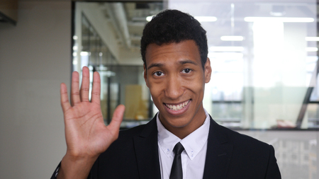 Hello, Waving Hand by Black Businessman in Suit in Officeの写真素材