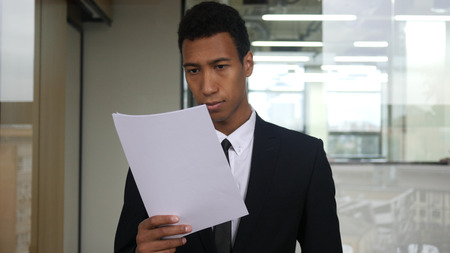 Black Businessman Reading Documents in Officeの写真素材