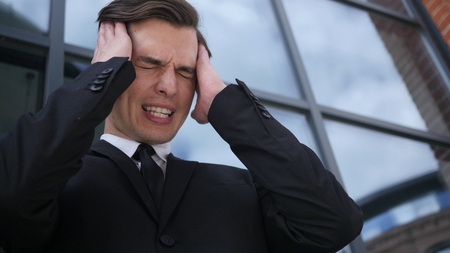 Frustrated, Tense Young Businessman with Headache and Problemsの写真素材