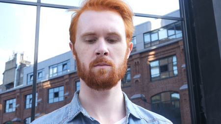 Serious Man with Beard and Red Hairs Looking downward, Outdoor Portraitの写真素材