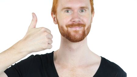 Portrait of happy man showing thumbs up while standing against white backgroundの写真素材
