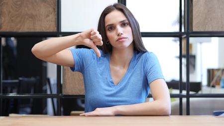 Thumbs Down By Beautiful Brunette Woman, Indoorの写真素材
