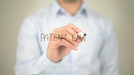 Patent Law, man writing on transparent screenの写真素材