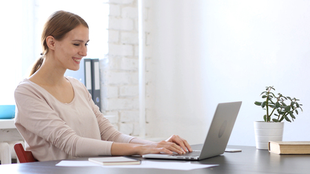 Smiling Beautiful Woman Working On Laptop in Officeの写真素材